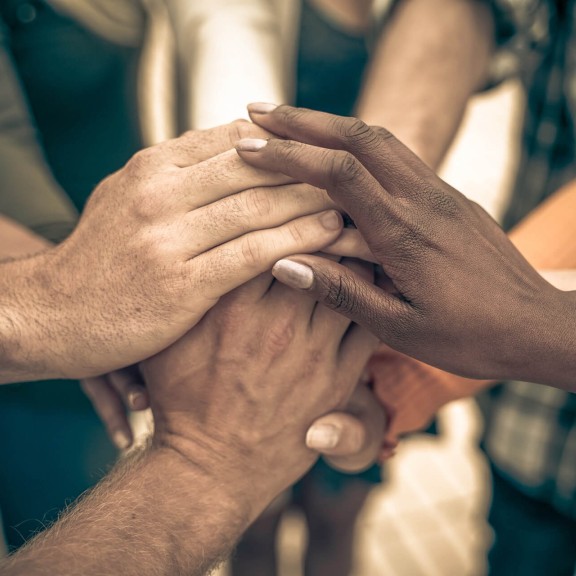 close-up of a diverse group of people's joined hands